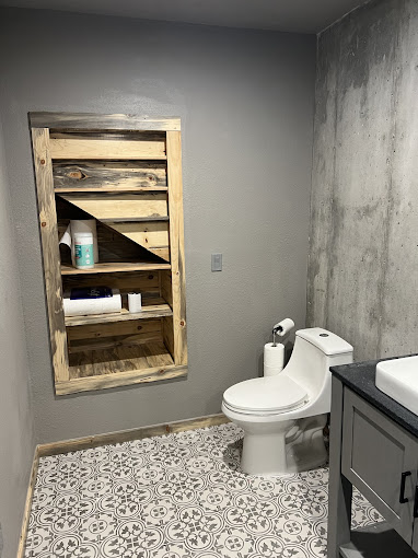 Bathroom with built-in reclaimed wood shelving and patterned tile floor in an Oklahoma barndominium