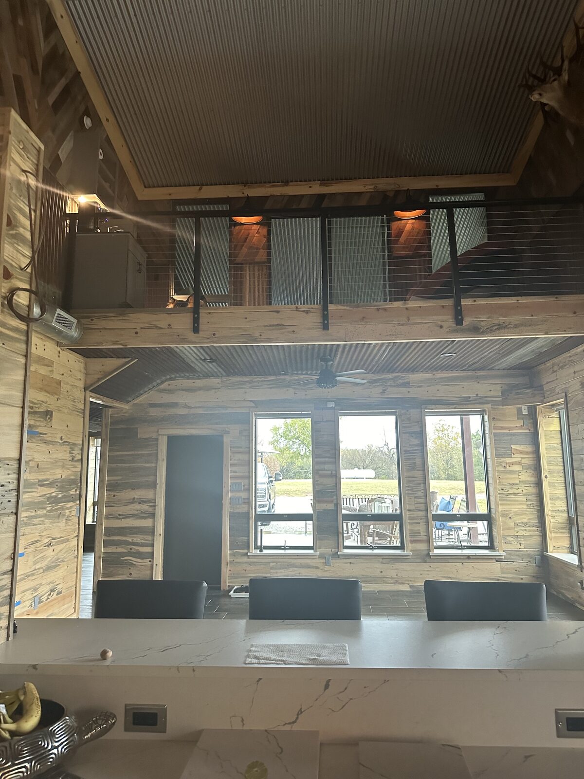 Two-story barndominium great room with loft, cable railing, and reclaimed wood walls in central Oklahoma