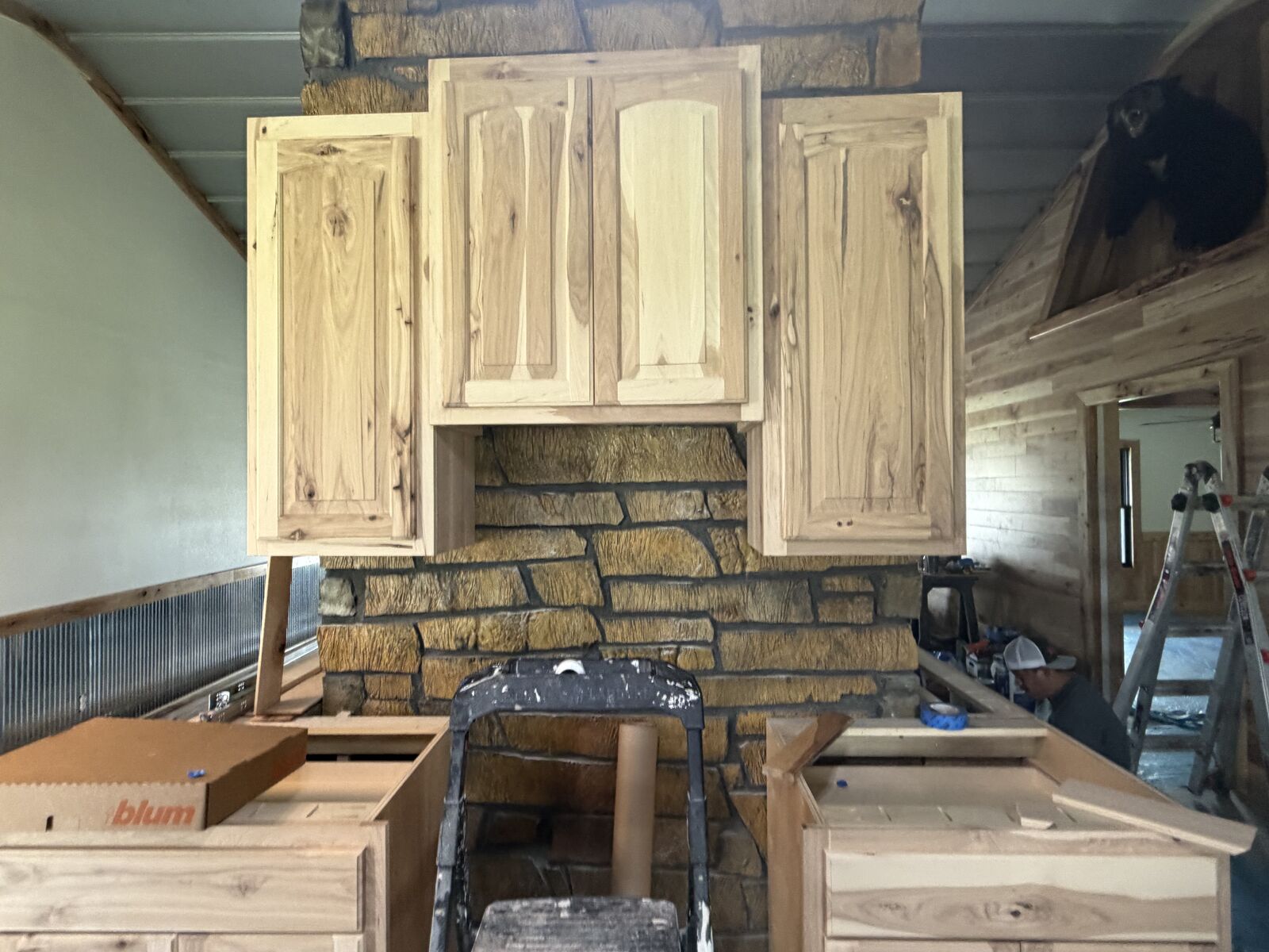 Custom hickory kitchen cabinets built around a stone fireplace in an Oklahoma barndominium