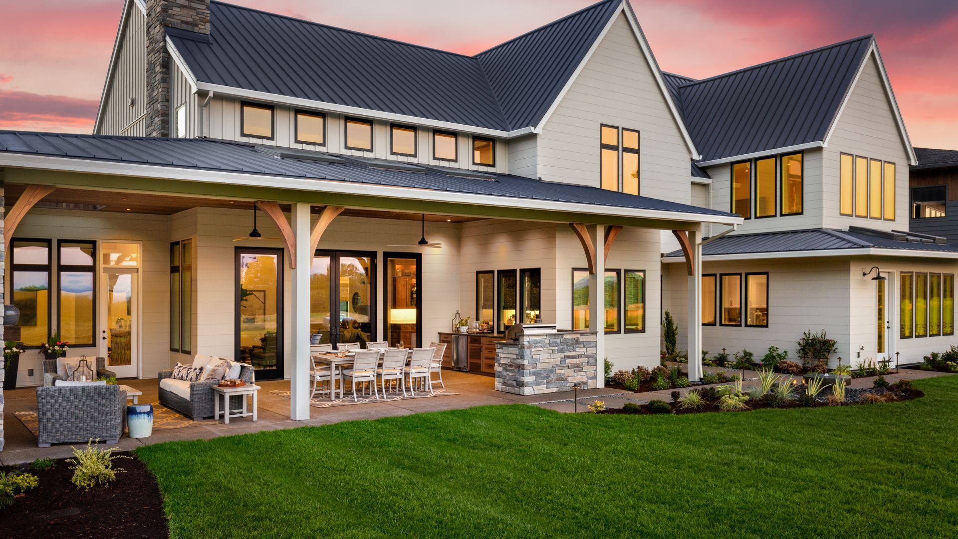 Modern farmhouse with metal roof and covered back porch at sunset