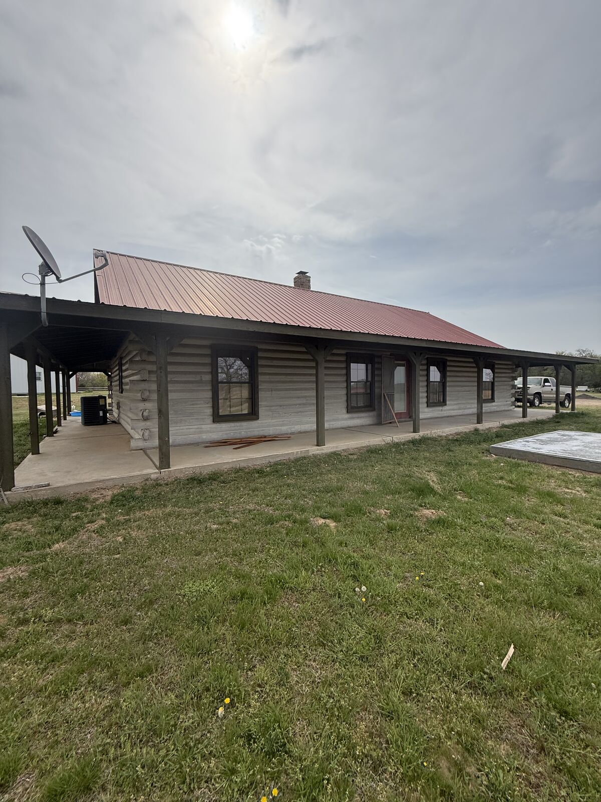 Metal roofing installation on a log home with wraparound porch in central Oklahoma