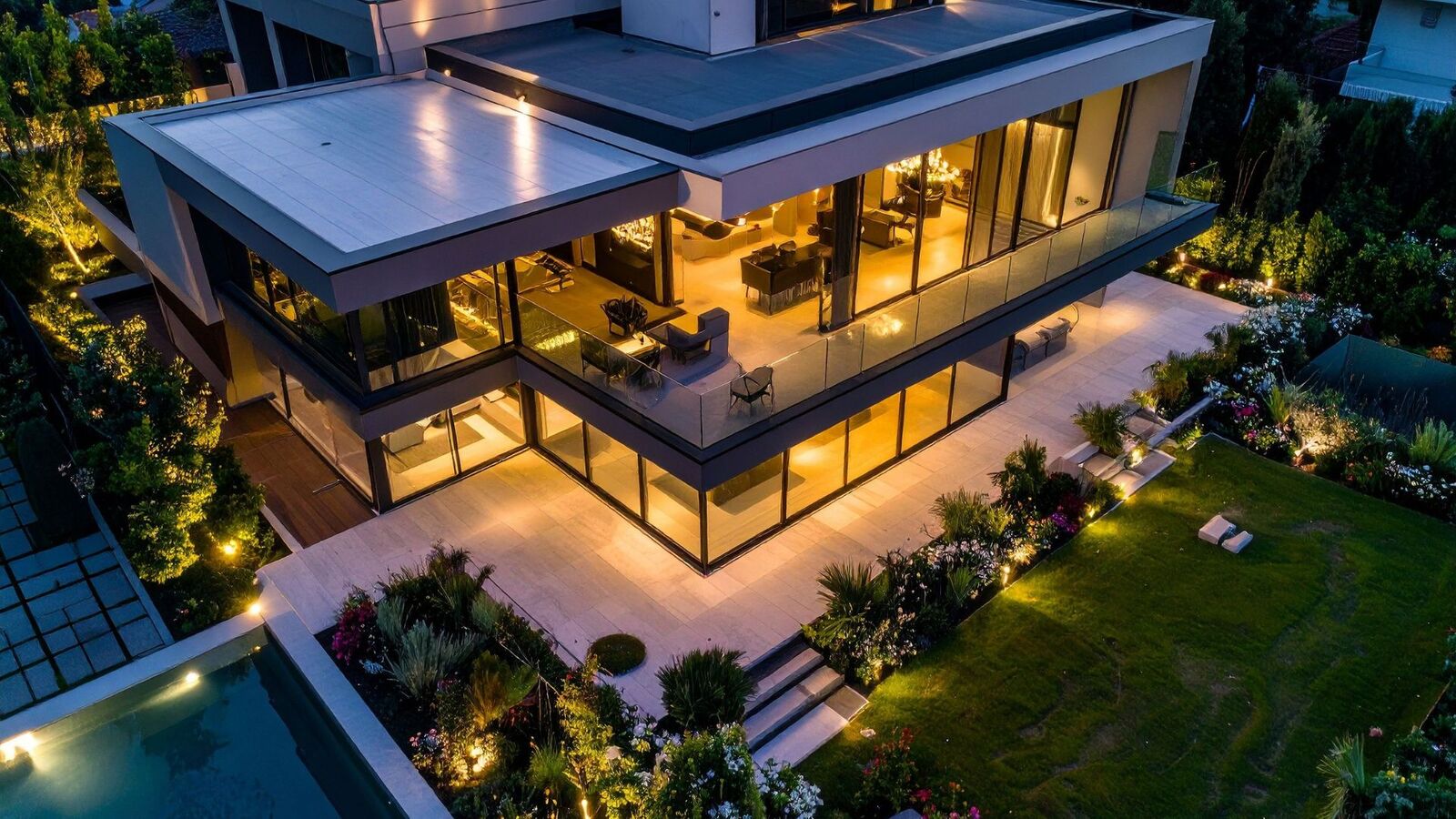 Aerial view of a modern custom home with outdoor living space at evening