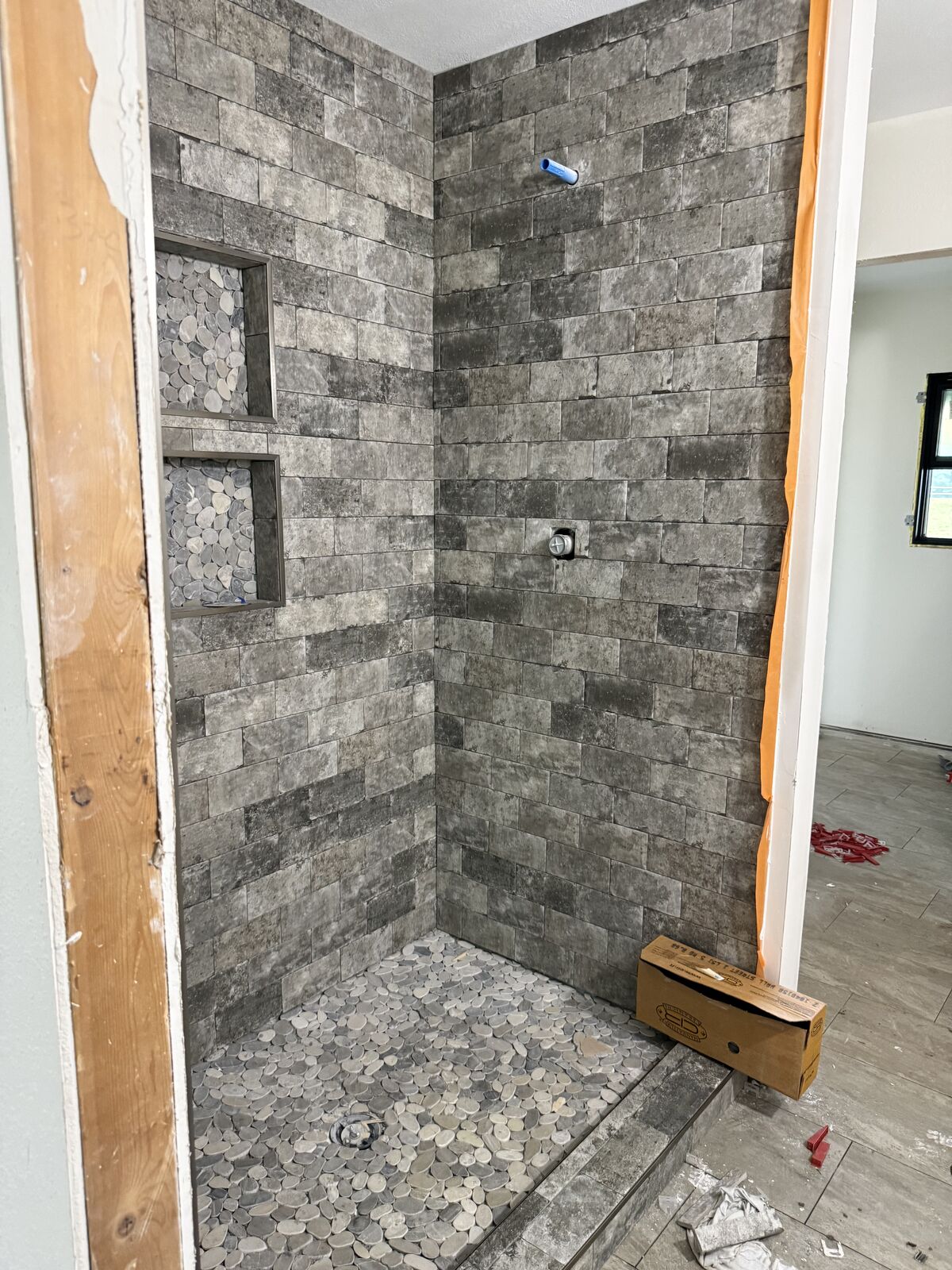 Stone-look tile walk-in shower with pebble floor from a bathroom renovation in Oklahoma
