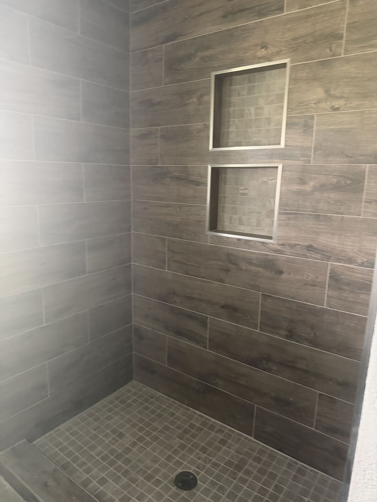 Wood-look tile shower surround with inset shelves during a bathroom remodeling project in Oklahoma