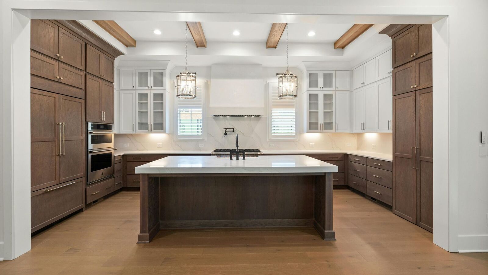 Two-tone kitchen remodel with exposed wood beams and large island
